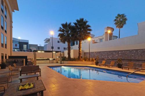 una piscina con sillas y palmeras junto a un edificio en Hampton by Hilton Chihuahua, en Chihuahua