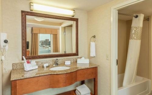 a bathroom with a sink and a mirror and a tub at Hampton by Hilton Queretaro Tecnologico in Querétaro