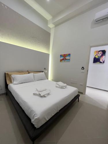 1 dormitorio con 1 cama blanca y 2 toallas en Dimora Chiaia 209 en Nápoles