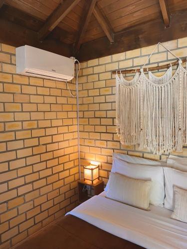 a bedroom with a white bed with a white air conditioner at Haleakala Hostel & Pousada in Praia do Rosa