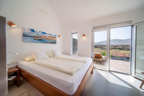 a white bedroom with a bed and a large window at Vaya Querida in Mala