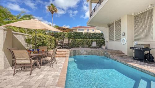 a swimming pool with a table and an umbrella next to a house at Villa Vista Mare - 675 in Siesta Key
