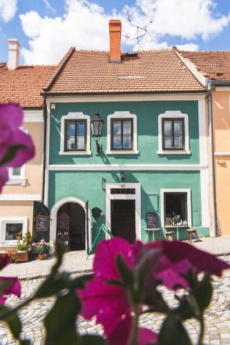 a green house with purple flowers in front of it at Olivea penzion & wine Mikulov in Mikulov