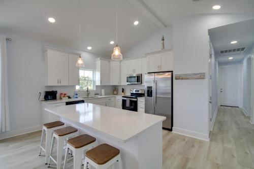 a kitchen with white cabinets and a large island with bar stools at Sunny Gulfport Vacation Rental Walk to Beaches! in Gulfport