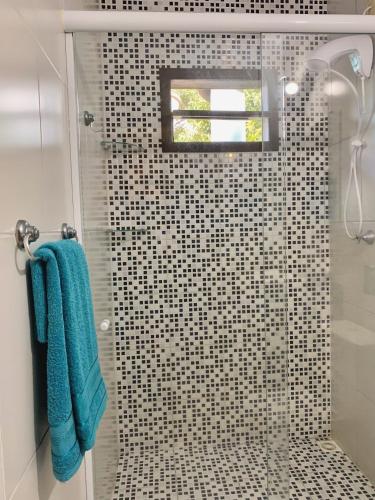 a bathroom with a shower with a blue towel at Haleakala Hostel & Pousada in Praia do Rosa