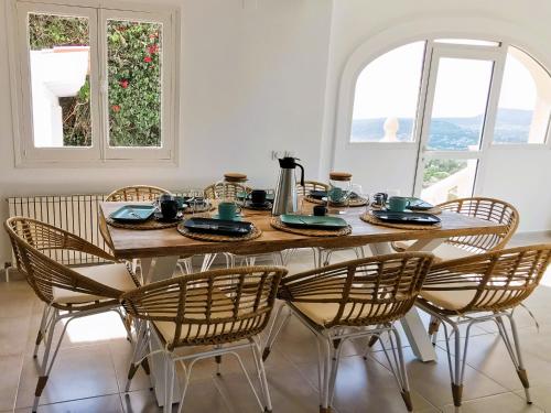 a dining room table and chairs with a table and two windows at Villa Panorama in Jávea