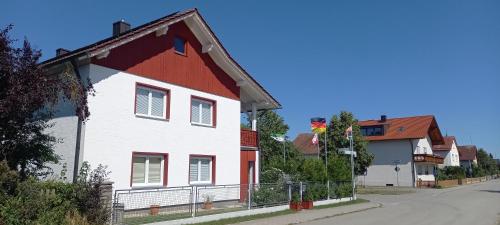 a red and white house on the side of a street at Gästehaus Grenzenlos in Aholfing