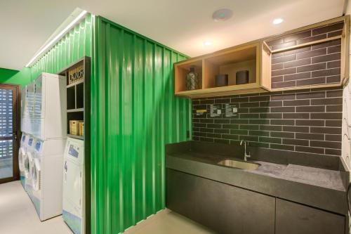 a green wall in a kitchen with a sink at Roomo Vila Mariana Vergueiro Residencial in Sao Paulo