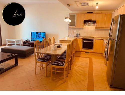 Beach front Apartment في طابا: مطبخ مع طاولة وكراسي وثلاجة