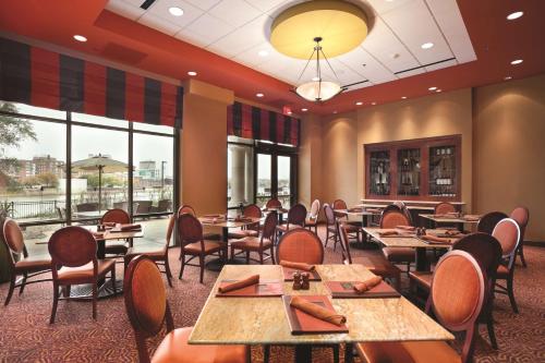 a dining room with tables and chairs and windows at Embassy Suites East Peoria Hotel and Riverfront Conference Center in Peoria