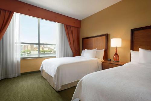 a hotel room with two beds and a large window at Embassy Suites East Peoria Hotel and Riverfront Conference Center in Peoria