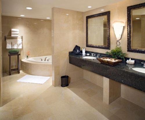 y baño con 2 lavabos, bañera y espejo. en Embassy Suites East Peoria Hotel and Riverfront Conference Center, en Peoria