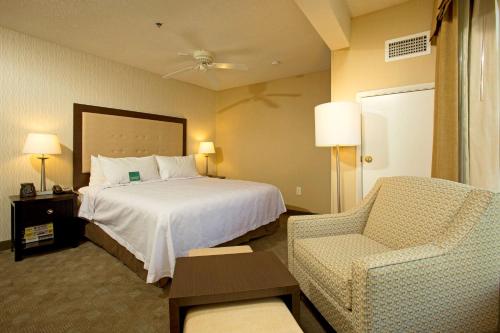 Pokój hotelowy z łóżkiem i krzesłem w obiekcie Homewood Suites by Hilton Alexandria w mieście Alexandria