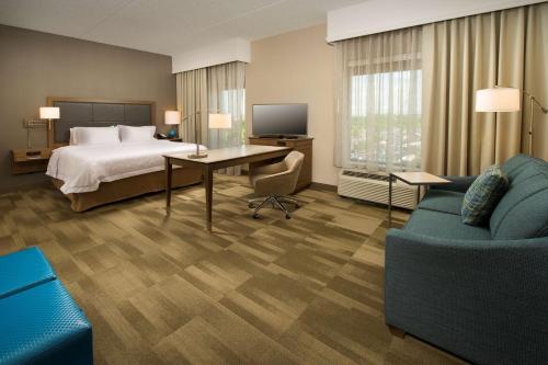 Hampton Inn & Suites Baltimore North/Timonium, MD في تيمونيوم: غرفة الفندق بسرير ومكتب واريكة