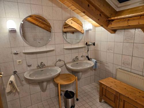 a bathroom with two sinks and two mirrors and a stool at Ferienhaus: idyllisch & erholsam in Eglofs
