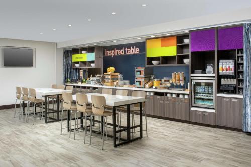 a kitchen with tables and chairs in a restaurant at Home2 Suites By Hilton Charlottesville Downtown in Charlottesville