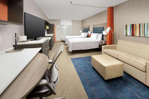 a hotel room with two beds and a couch at Home2 Suites By Hilton Charlottesville Downtown in Charlottesville