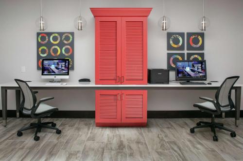 an office with red doors and a desk with two monitors at Home2 Suites By Hilton Charlottesville Downtown in Charlottesville