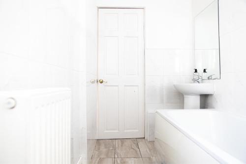 a white bathroom with a sink and a white door at Daze Private 1BR Near to City Centre in Liverpool