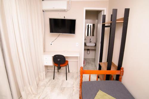 a room with a desk with a tv and a chair at ASP hospedaria in Paranaguá