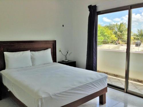 a bedroom with a bed and a large window at Posada Malix Pek in Tulum