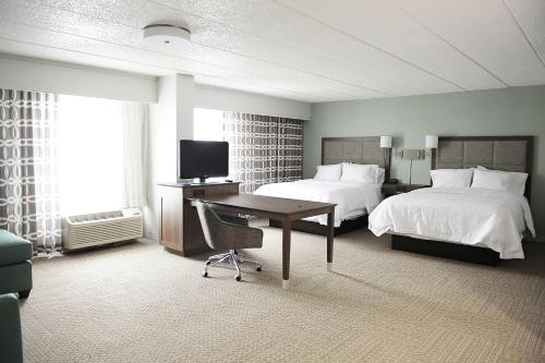 Habitación de hotel con 2 camas, escritorio y TV. en DoubleTree by Hilton Dulles Airport-Sterling en Sterling