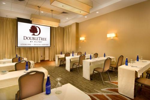 a dining room with tables and chairs and a screen at DoubleTree by Hilton Dulles Airport-Sterling in Sterling
