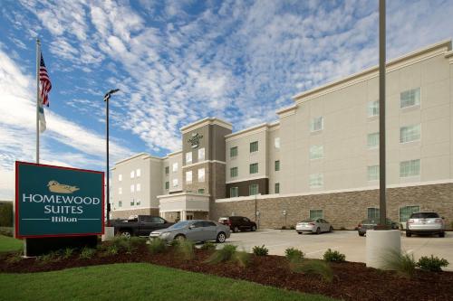 a sign in front of a hotel with cars parked in a parking lot at Homewood Suites by Hilton Metairie New Orleans in Metairie