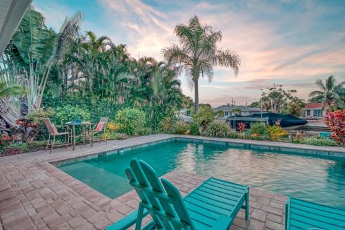 a swimming pool with two blue chairs and a table at La Contento Casa - 5560 in Siesta Key