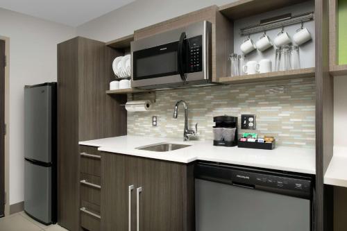 a kitchen with a sink and a microwave and a refrigerator at Home2 Suites By Hilton Phoenix Airport South in Phoenix