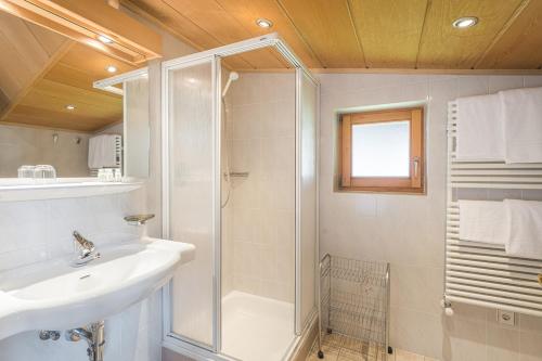 uma casa de banho branca com um lavatório e um chuveiro em B&B Ciauceia em Selva di Val Gardena