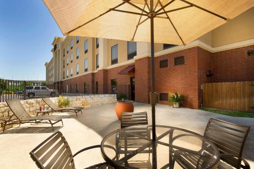 a patio with a table and chairs and an umbrella at Hampton Inn and Suites San Antonio Airport in San Antonio