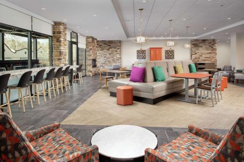 a lobby with a couch and tables and chairs at Home2 Suites By Hilton Asheville Biltmore Village in Asheville