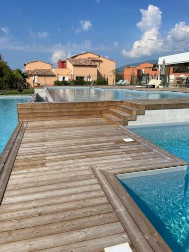 - une passerelle en bois au-dessus de l'eau dans une piscine dans l'établissement Résidence les Hameaux de Saint Cyprien appartement LUNA 132, à Lecci