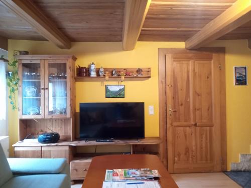 a living room with a tv and a wooden door at Ferienwohnung zum Sebnitzer Hirsch in Sebnitz