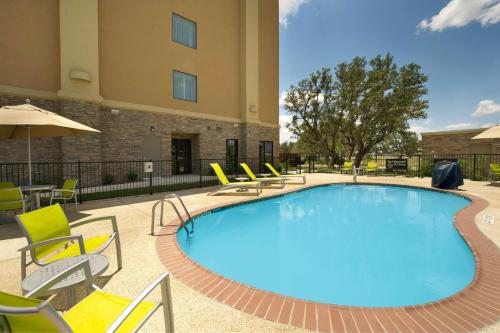 ユバルディにあるHampton Inn Uvaldeの椅子と建物のある大きなプール