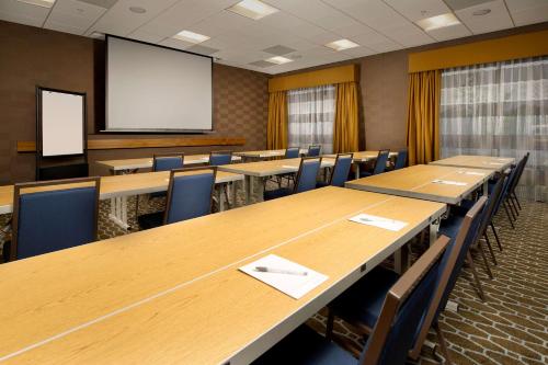 a conference room with tables and chairs and a screen at Hampton Inn and Suites Washington DC North/Gaithersburg in Gaithersburg