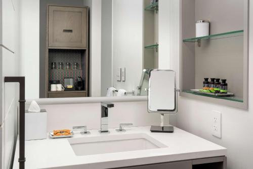 a white bathroom with a sink and a mirror at Canopy By Hilton Ithaca Downtown in Ithaca