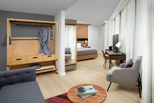 a living room with a bed and a room with a desk at Canopy By Hilton Ithaca Downtown in Ithaca