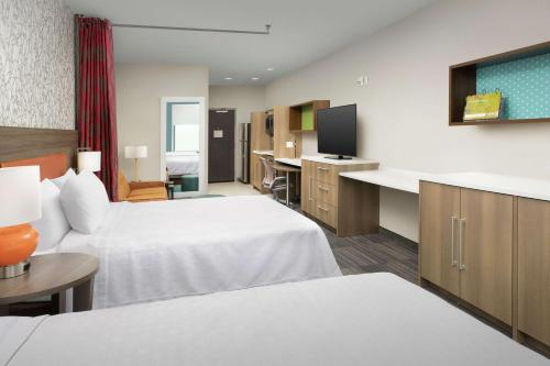 a hotel room with two beds and a flat screen tv at Home2 Suites by Hilton San Antonio Lackland SeaWorld in San Antonio