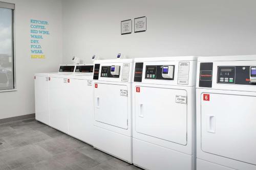 a row of white washing machines lined up against a wall at Home2 Suites by Hilton San Antonio Lackland SeaWorld in San Antonio