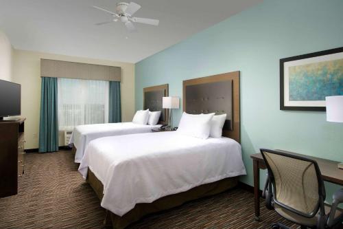 a hotel room with two beds and a desk at Homewood Suites San Antonio Airport in San Antonio