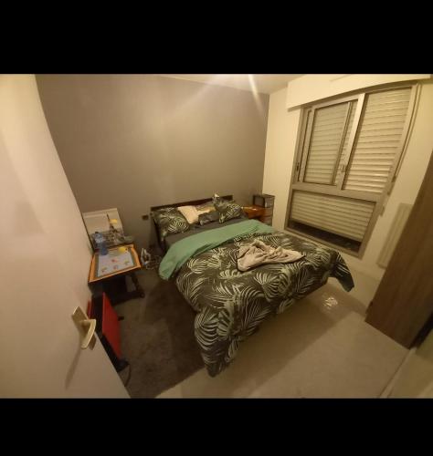 um quarto com uma cama com um edredão e uma janela em idéal pour vacances et affaires em Perpignan