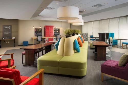 a waiting room with a couch and tables and chairs at Home2 Suites by Hilton Arundel Mills BWI Airport in Hanover