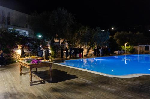 a swimming pool at night with people standing around it at Agriturismo Giorgio in Mattinata