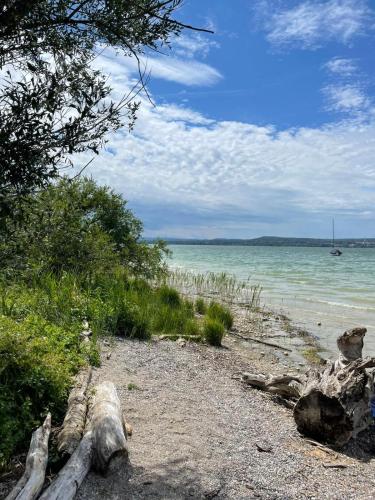 a sandy beach with a boat in the water at Seenswert - Vegane Pension und Ferienwohnungen am Ammersee in Pähl