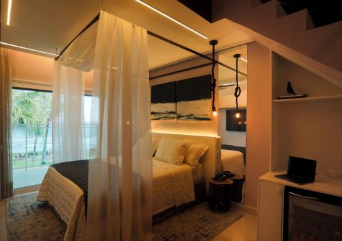 a bedroom with a canopy bed with a window at Amora Hotel Maresias in Maresias