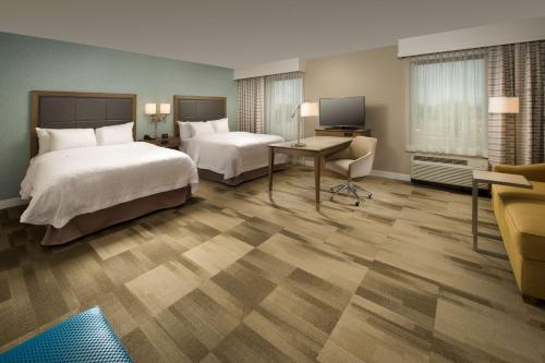 ein Hotelzimmer mit 2 Betten und einem Schreibtisch in der Unterkunft Hampton Inn & Suites Syracuse/Carrier Circle in East Syracuse