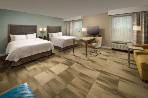 a hotel room with two beds and a desk at Hampton Inn & Suites Syracuse/Carrier Circle in East Syracuse