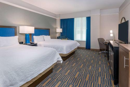 a hotel room with two beds and a desk at Hampton Inn & Suites Buffalo/Downtown in Buffalo